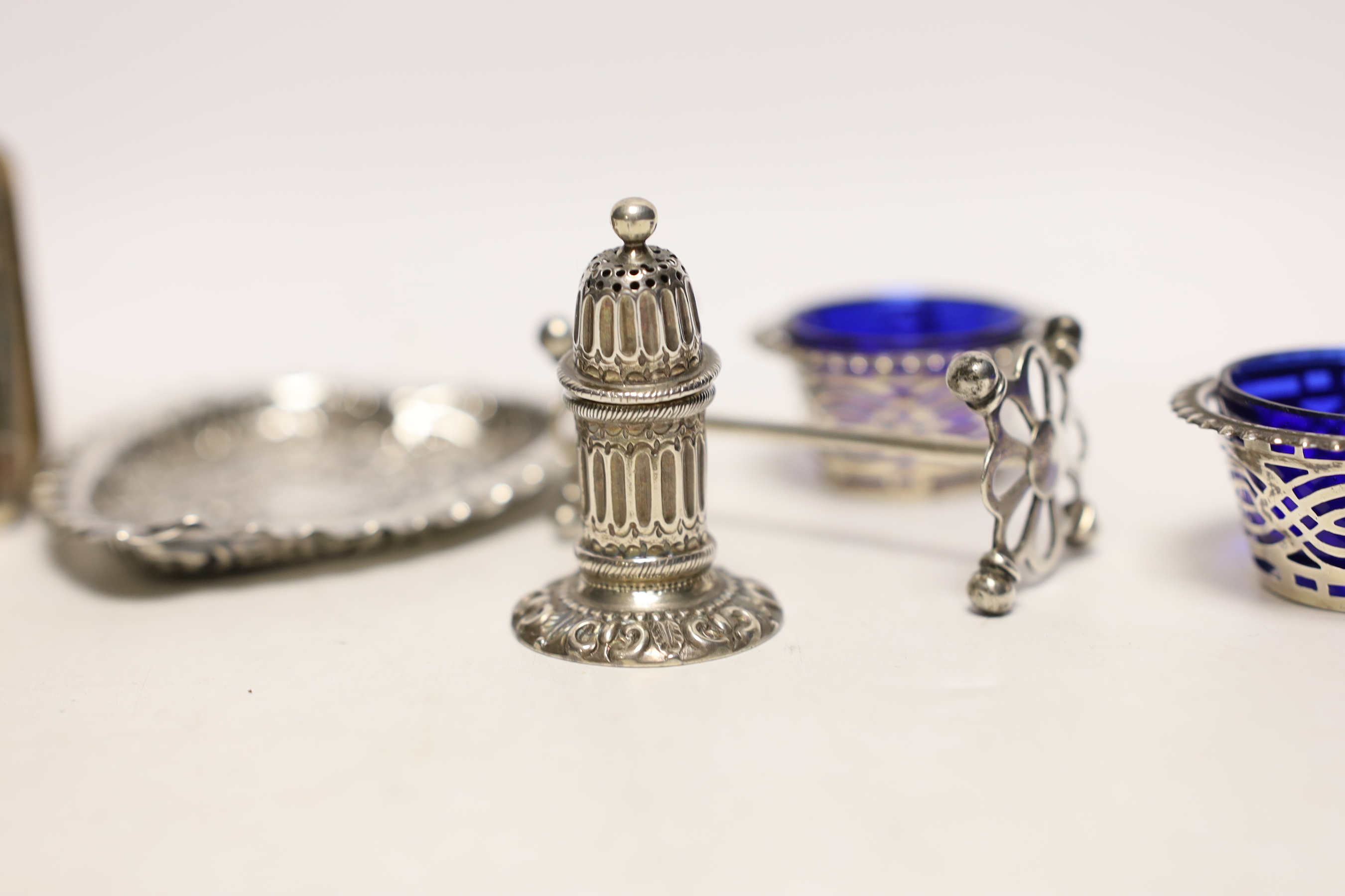 An Edwardian repousse silver mounted small bible, a silver circular pill box, a pair of silver salts, silver pepperette, pair of silver knife rests and a heart shaped dish.